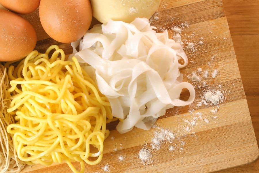 Rice Noodles vs Egg Noodles: egg noodles and raw eggs on a wooden plate