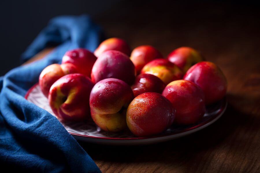 A group of colorful nectarine fruits or peach on a plate